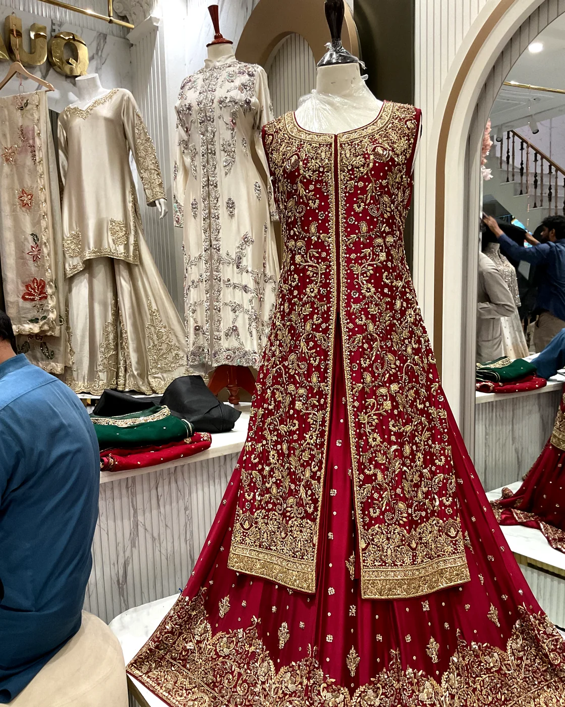 Red bridal gown with a long embroidered jacket over a flared lehanga