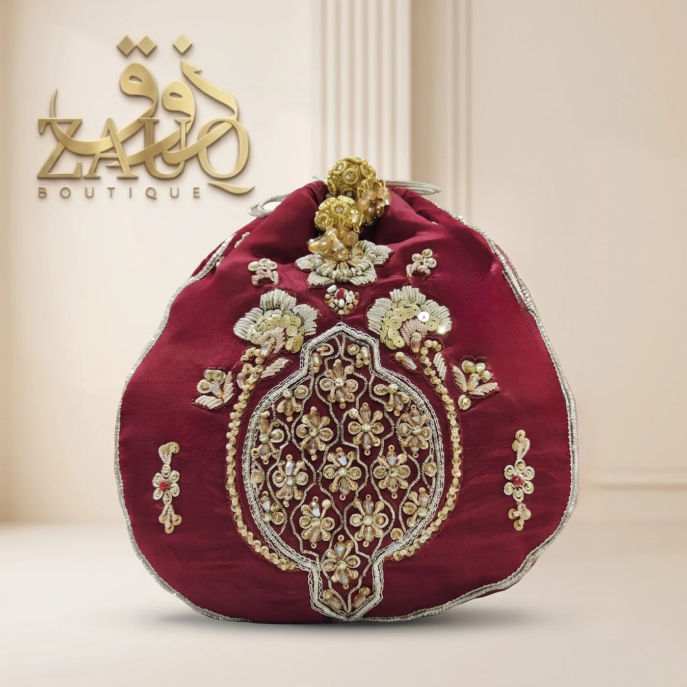 A crimson U-shaped potli with raised gold and ivory floral work.
